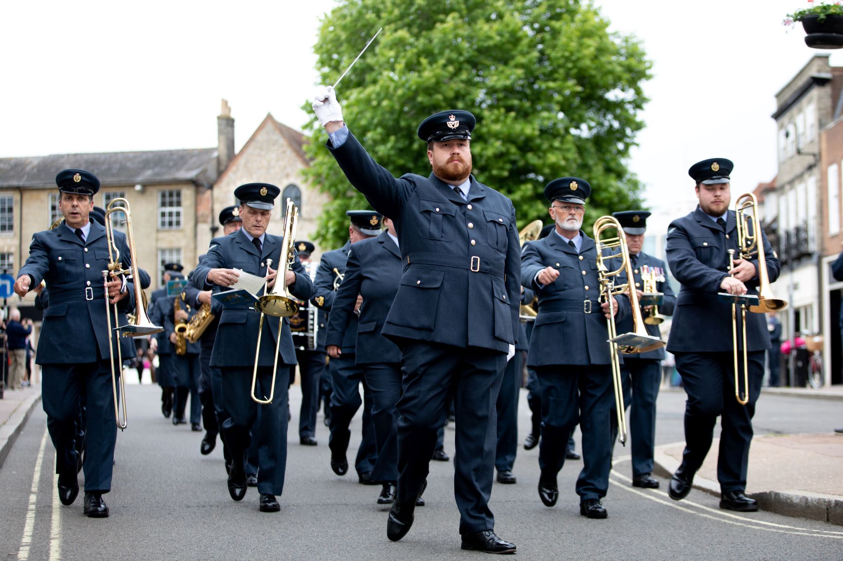 RAF Musicians parade through streets with brass instruments.